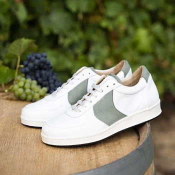 Deux chaussures de basket blanches et vertes devant des grappes de raisins
