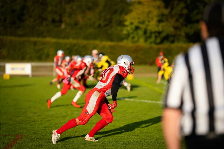 un joueur en tenue rouge face à une défense de cover 4 au football américain